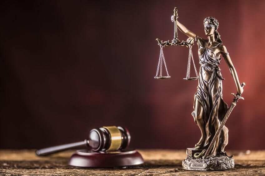 Lady Justicia holding sword and scale bronze figurine with judge hammer on wooden table